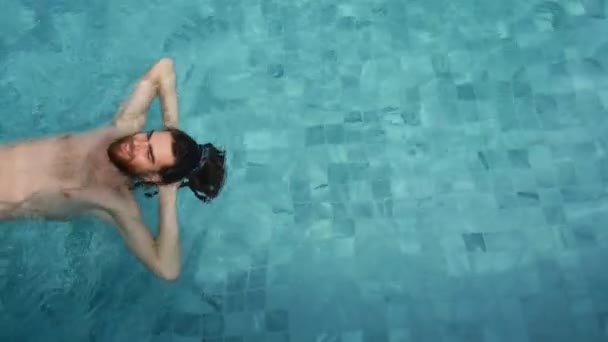 Ένας άντρας κολυμπάει στην πισίνα, με θέα στην κορυφή. Ευτυχισμένος τύπος σε dreadlocks διακοπές — Αρχείο Βίντεο