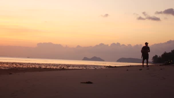 Un uomo cammina lungo il lungomare al tramonto — Video Stock