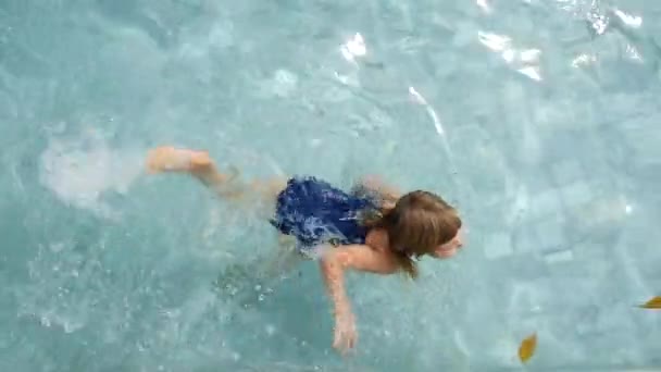 Barnet lærer å svømme i bassenget. – stockvideo