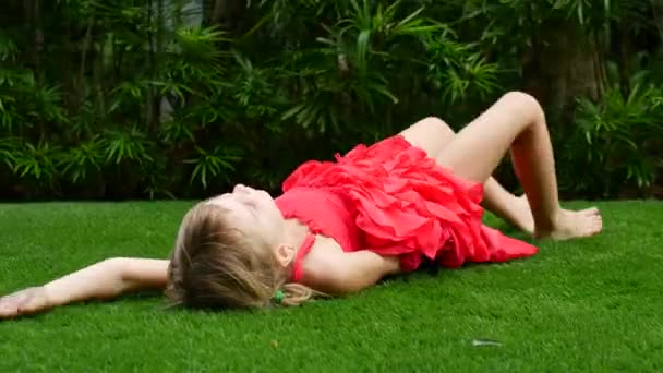 Girl child rides on the green grass. Walk in the fresh air, a girl rolls along the grass — Stock Video