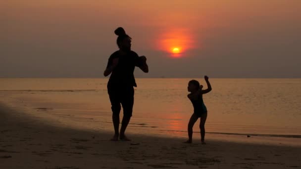 Papa en kind springen bij zonsondergang op het strand — Stockvideo