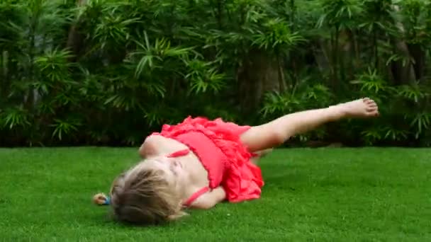 Girl child rides on the green grass. Walk in the fresh air, a girl rolls along the grass — Stock Video