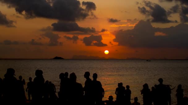 Uma festa na praia ao pôr-do-sol. Pessoas irreconhecíveis admiram o pôr-do-sol no mar — Vídeo de Stock