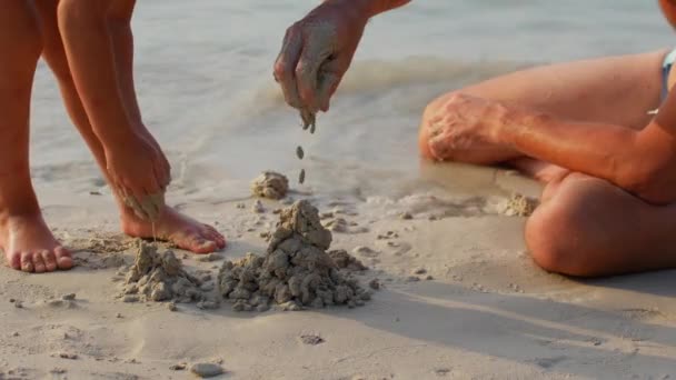 Padre e figlia costruiscono un castello di sabbia sulla spiaggia — Video Stock