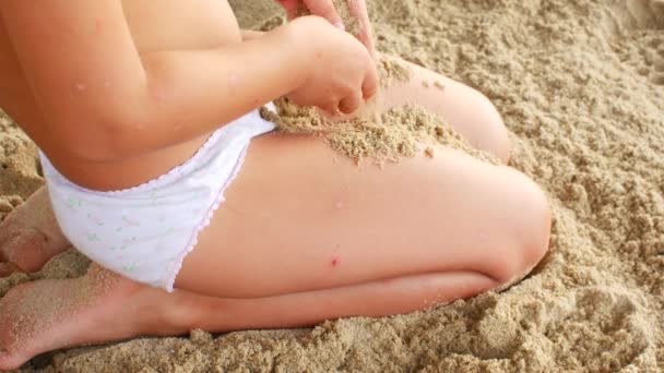 Неузнаваемый ребенок закопал ноги в песок на пляже. — стоковое видео