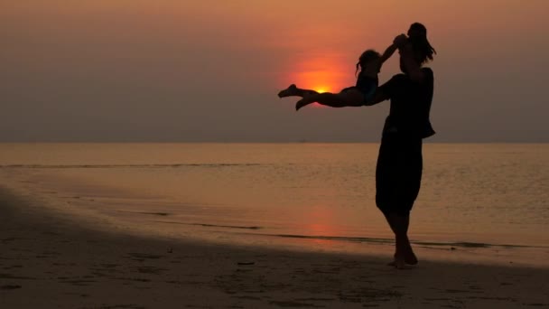 Pai e criança pulam na praia ao pôr do sol — Vídeo de Stock