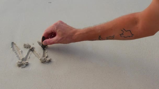 En man hand skriver ordet Arbeta på sanden och spolar bokstäverna med en våg — Stockvideo