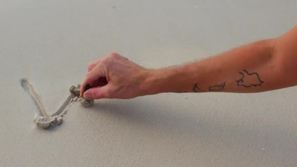 Ένα αντρικό χέρι γράφει τη λέξη "Δούλεψε στην άμμο" και ξεπλένει τα γράμματα με ένα κύμα. — Αρχείο Βίντεο