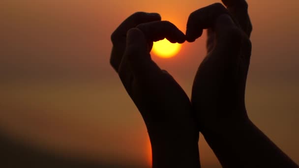 日没の背景に指から心臓のジェスチャーを表示します。 — ストック動画