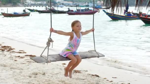 Child girl on a swing near the sea — Stockvideo