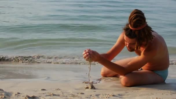 En man bygger ett sandslott på stranden — Stockvideo