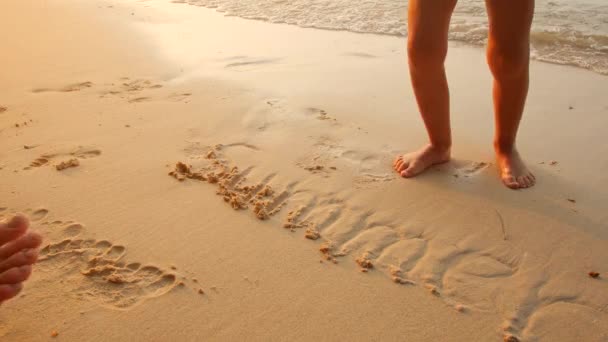 Kind läuft barfuß im Sand, wo das Wort Sommer geschrieben steht — Stockvideo