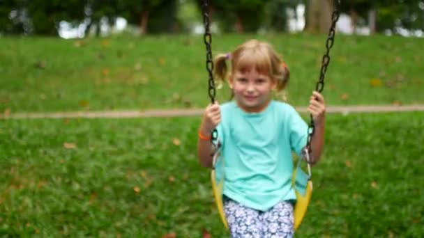 Девочка катается на качелях в парке — стоковое видео