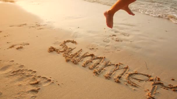 Kind läuft barfuß im Sand, wo das Wort Sommer geschrieben steht — Stockvideo