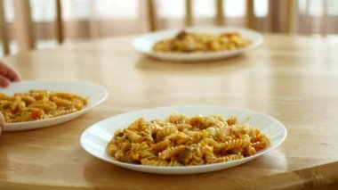 The child rearranges plates of pasta on the table. 