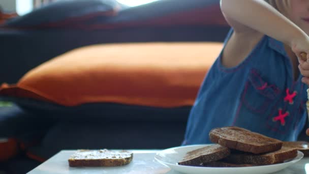 Girl child spreads toast with peanut butter — Stockvideo
