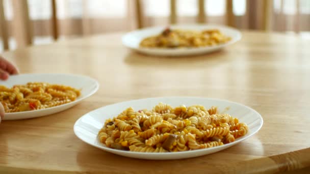 The child rearranges plates of pasta on the table. — ストック動画