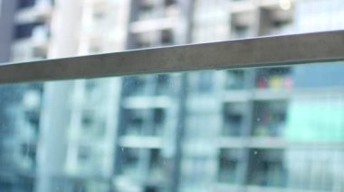 A little girl peeks over a glass railing.