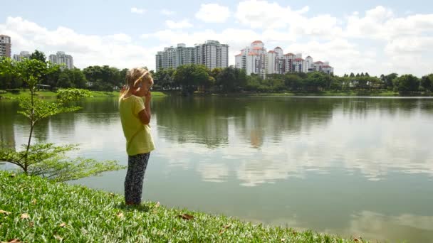 A girl is looking out for fish in a pond. — 비디오