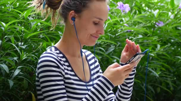Una joven escucha música y se comunica con amigos en Internet . — Vídeos de Stock