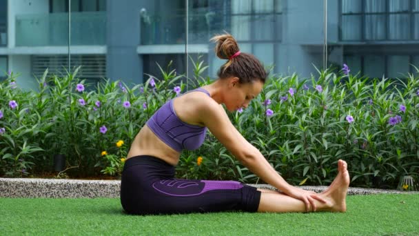 Young woman doing stretching on the grass — Stock Video