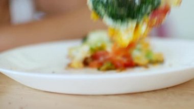 Bir çocuk çatallı sebzeli sahanda yumurta seçiyor. Yakın plan.