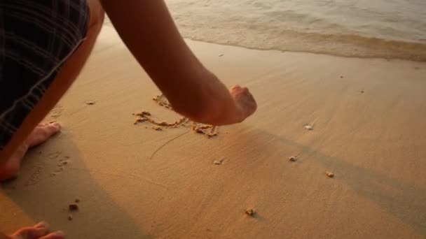 Un uomo scrive una parola sulla sabbia, concetto di vacanza estiva — Video Stock