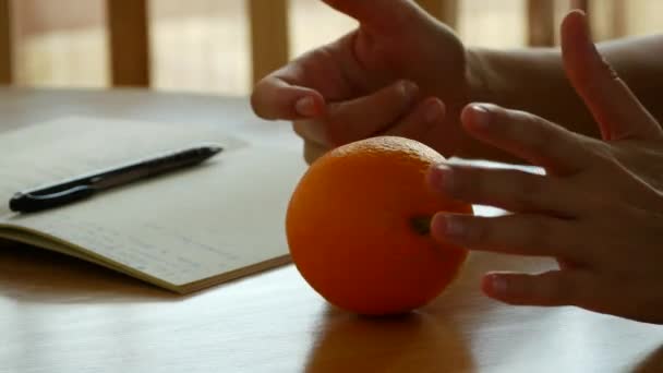 La chica sostiene una naranja en sus manos. Pausa para el almuerzo en la oficina — Vídeos de Stock