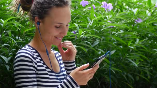 A young woman listens to music and communicates with friends on the Internet. — ストック動画