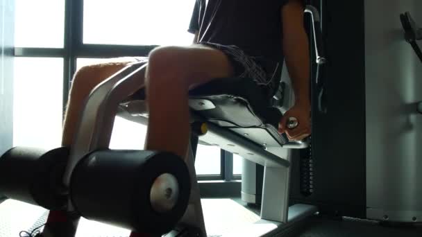 Adam spor salonundaki simülatörde bacak çalıştırıyor. — Stok video