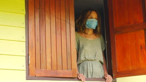 Мама и дочь в защитных масках в окне. Пандемия, карантин, вирус. COVID-19 — стоковое видео