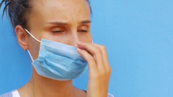 Een jonge vrouw met een masker blaast haar neus met een papieren servet. — Stockvideo