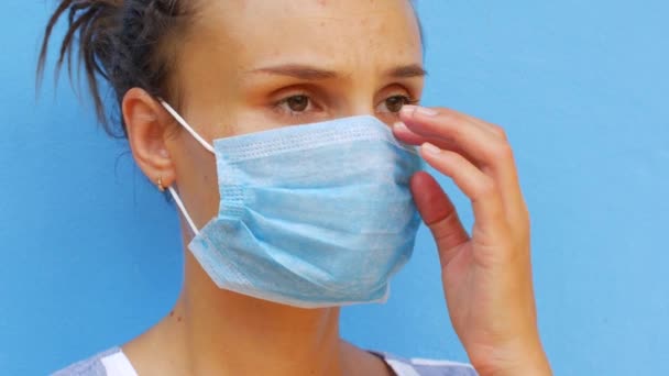 Een jonge vrouw met een masker blaast haar neus met een papieren servet — Stockvideo