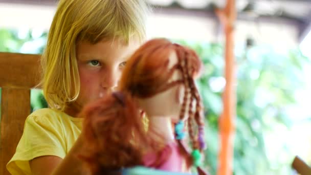 Mädchen im Vorschulalter macht Frisurpuppe. Heimspiele beim Friseur — Stockvideo