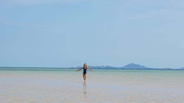 Ένα εξάχρονο κορίτσι τρέχει στα ρηχά νερά. Θάλασσα — Αρχείο Βίντεο