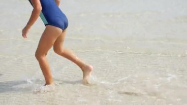6 yaşında bir kız sığ sularda koşuyor. Deniz