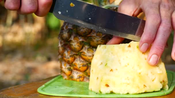 Een man snijdt een ananas, close-up — Stockvideo