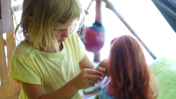 Mädchen im Vorschulalter macht Frisurpuppe. Heimspiele beim Friseur — Stockvideo