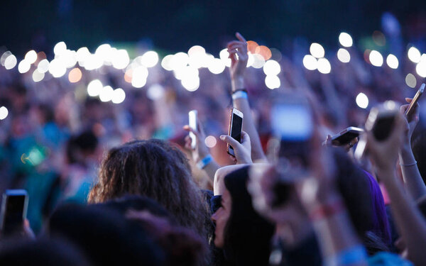 Music fan filming concert with smart phone in hand