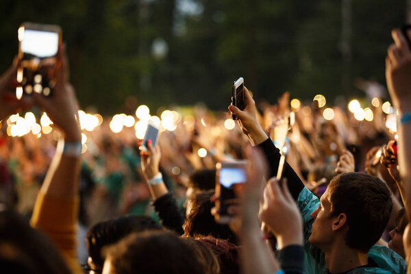 Music fan filming concert with smart phone in hand