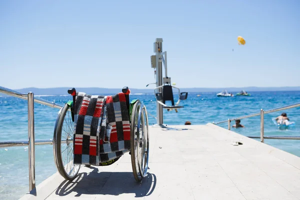 Кресло-каталка и подъемный кран позволяют инвалидам добраться до воды — стоковое фото