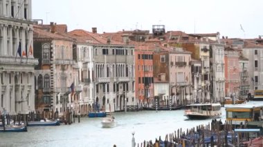 VENICE,ITALY-4 MAY,2019:Motor boat in Grand Canal shot from Rialto Bridge in Venice.The most popular tourist place in Venezia.Old Italian houses and gondola boats drifting on waves in rainy spring day