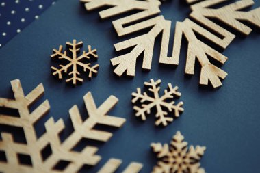 Mutlu yıllar ve Noel arifesi kutlamaları için güzel eller kar taneleri yaptı. Mavi arka planda el yapımı ahşap kar taneleri figürleri. Solan film renkleriyle düzenlenmiş, yukarıdan çekilmiş.
