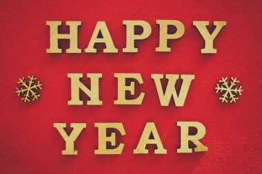 Mutlu yıllar. El yapımı ev dekorasyonu. Canlı kırmızı arka planda ahşap harfler. Eski film filtresiyle düzenlenmiş kış tatili duvar kağıdı.