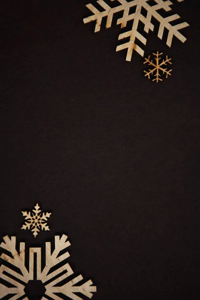 手で作られた木製の雪のフレークで濃い茶色の色のハッピーニューイヤーとクリスマスイブの背景 木から作られた手作りの雪片で飾られたテキストのための空のスペースと冬の休日の壁紙 — ストック写真