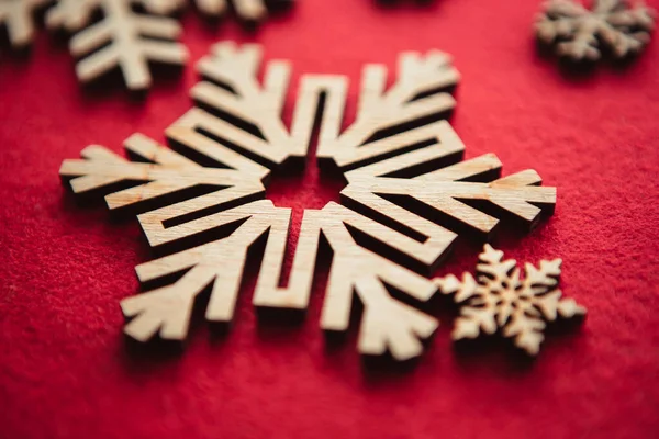 冬の休日の装飾のための手作りの木製の雪片 赤い背景に天然木から作られた素朴なスタイルの家の装飾オブジェクト — ストック写真