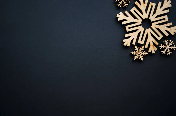 クリスマスと新年の背景手は冬の休日の壁のための黒の背景に素朴な木製の雪のフレークを作りました — ストック写真