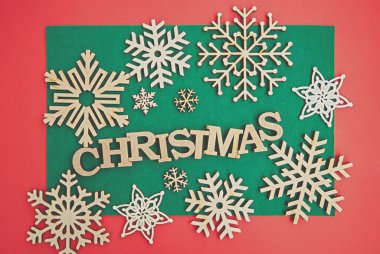 Noel arkaplanı düzdü. El yapımı ahşap kar taneleri ve kış tatili yürüyüşü tasarımları için kırmızı arkaplan üzerinde mektuplar. Ekolojik kırsal ahşap dekor yukarıdan yakın çekim