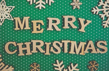 Düz yeşil bir Noel arkaplanı vardı. Kırsal ahşap harfler ve kar taneleri. Kış tatili duvar kağıtları için el işi.