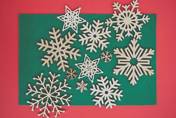 クリスマスをテーマにした背景にフラットレイで手作りの木製の雪片 冬の休暇のための手作りの工芸品と赤 緑の背景 — ストック写真
